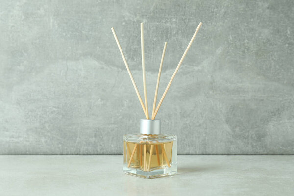 Diffuser bottle with sticks against gray textured background