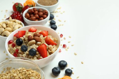 Beyaz arka planda bir kase yulaf ezmesi ve malzeme.