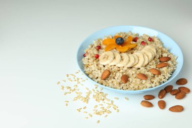 Beyaz arka planda bir kase yulaf ezmesi ve malzeme.