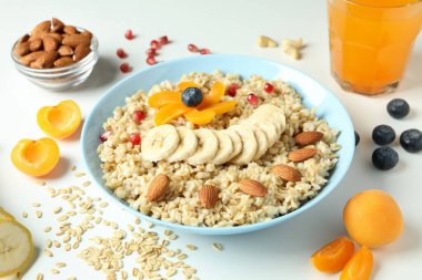 Beyaz arka planda bir kase yulaf ezmesi ve malzeme.