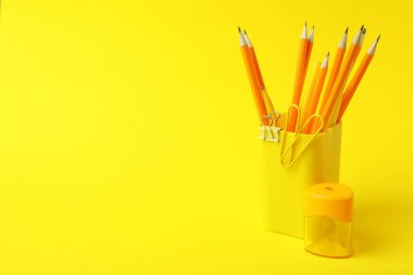 Sarı arkaplanda farklı kırtasiye malzemesi olan tutucu