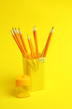 Sarı arkaplanda farklı kırtasiye malzemesi olan tutucu