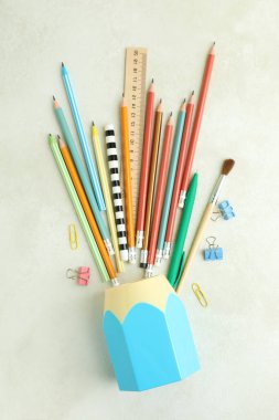 Beyaz desenli masa üzerinde kırtasiye malzemesi olan tutucu