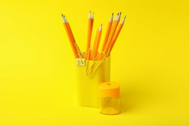 Sarı arkaplanda farklı kırtasiye malzemesi olan tutucu