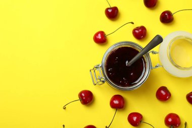 Sarı arka planda kiraz reçeli ve malzemeler