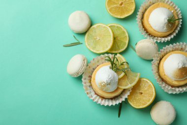 Lemon cupcakes, macaroons and ingredients on mint background