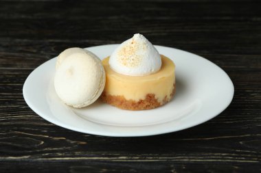 Plate with cupcake and macaroons, and lemons on wooden table