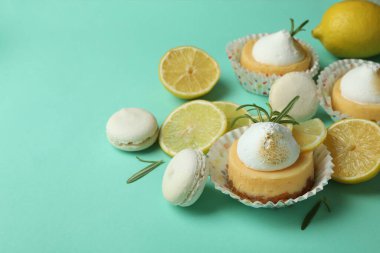 Lemon cupcakes, macaroons and ingredients on mint background