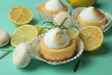 Lemon cupcakes, macaroons and ingredients on mint background