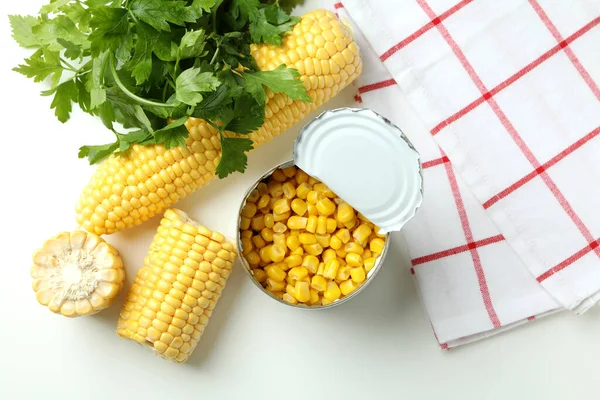 Raw corn and canned corn on white table