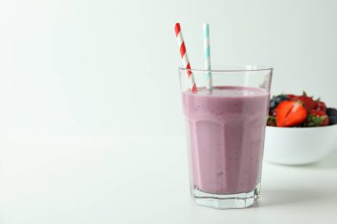 Beyaz arka planda bir bardak smoothie ve malzemeler