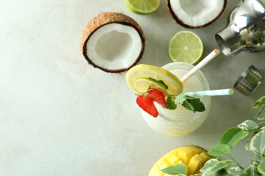 Bir bardak tropikal kokteyl ve beyaz desenli masa malzemeleri.