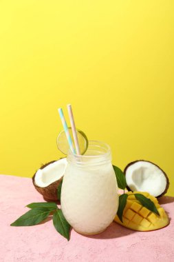 Pembe masada bir bardak tropik kokteyl ve malzemeler.