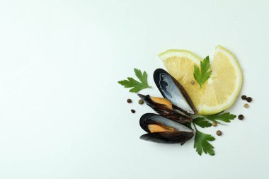 Beyaz arka planda limonlu midye, maydanoz ve biber.