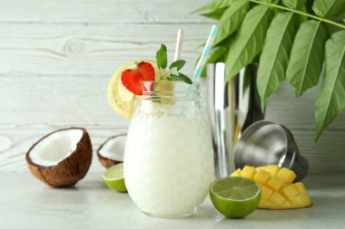 Bir bardak tropikal kokteyl ve beyaz desenli masa malzemeleri.