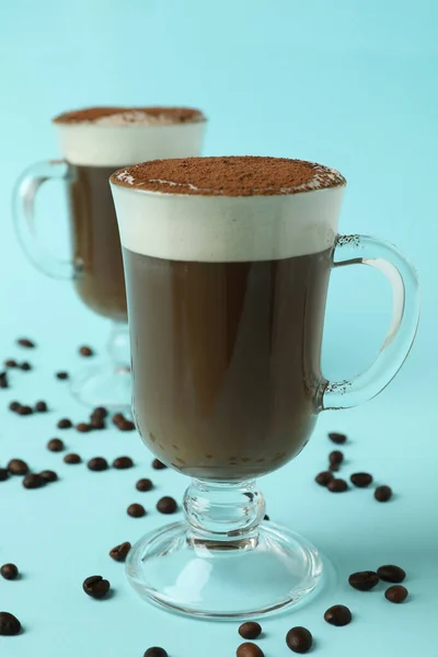 Glasses of irish coffee and coffee seeds on blue background