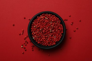 Kırmızı arka planda siyah biber kasesi.