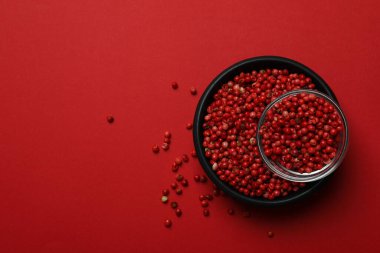 Kırmızı arka planda siyah biber kasesi.