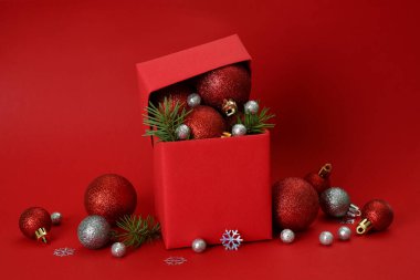 Kırmızı arka planda hediye kutusu ve Noel mücevherleri