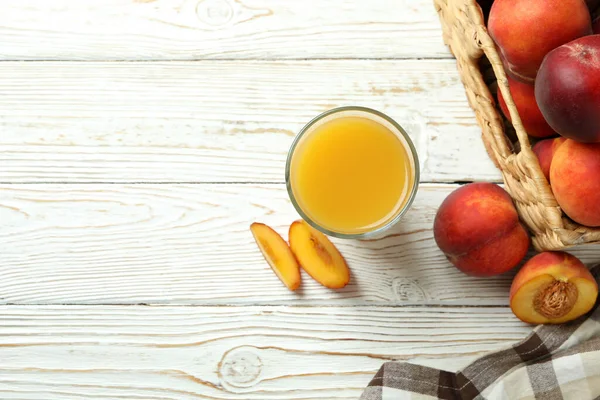 白い木のテーブルの上に桃ジュースと桃の果物のガラス — ストック写真