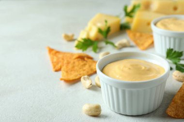 Peynir sosu ve abur cuburlar beyaz desenli masada.