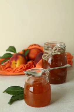 Şeftali reçeli ve malzemeler beyaz desenli masada.