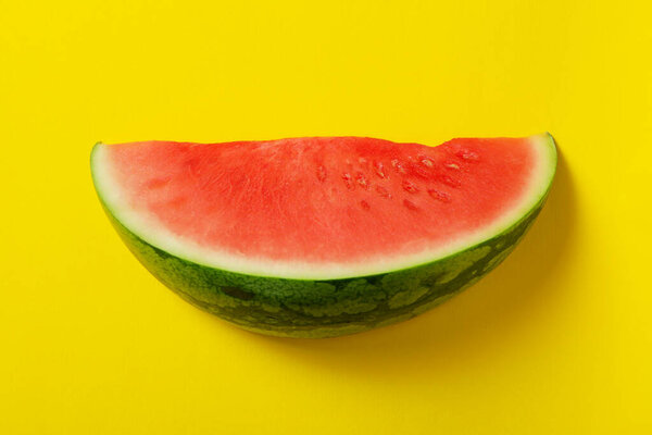 Ripe juicy watermelon slice on yellow background