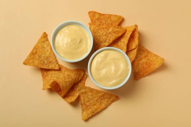 Peynir soslu kaseler ve bej arka planda cipsler.