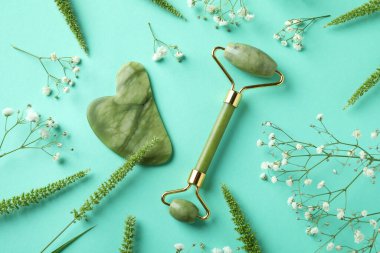 Yüz silindirli cilt bakımı konsepti ve nane arkaplanda gua sha