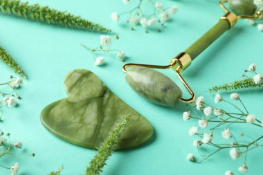 Yüz silindirli cilt bakımı konsepti ve nane arkaplanda gua sha