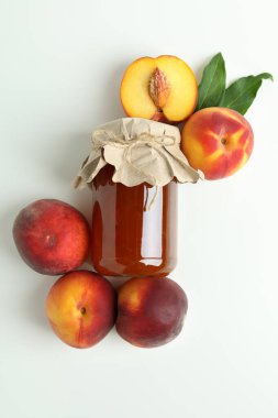 Şeftali reçeli kavanozu ve beyaz arka planda malzemeler