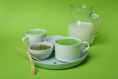 Yeşil arka planda yapmak için bir fincan matcha latte ve aksesuarlar.