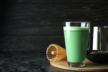 Siyah dumanlı masayı hazırlamak için bir bardak matcha latte ve aksesuarlar.