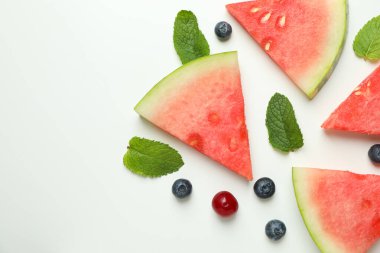 Beyaz arka planda karpuz dilimleri ve böğürtlenlerle yatıyordu