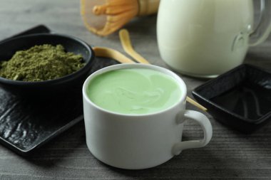 Gri desenli masada yapmak için bir fincan kibrit latte ve aksesuarlar.