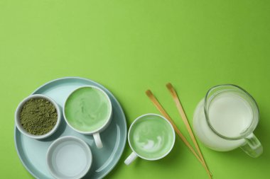 Yeşil arka planda yapmak için bir fincan matcha latte ve aksesuarlar.