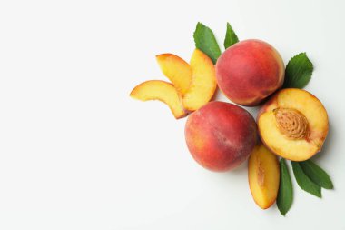 Beyaz arka planda yaprakları olan olgun şeftali meyveleri.