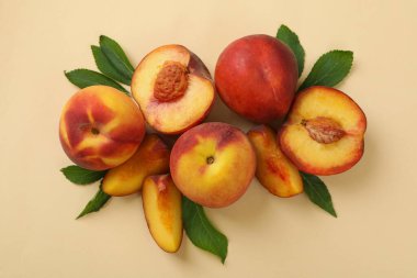 Bej arka planda yaprakları olan olgun şeftali meyveleri
