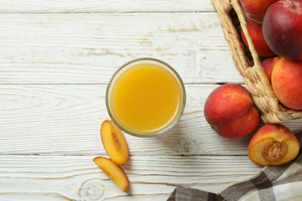 白い木のテーブルの上に桃ジュースと桃の果物のガラス — ストック写真