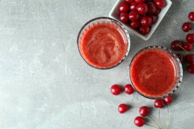 Bir bardak vişne suyu ve gri desenli masa malzemesi.