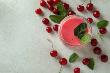 Glass jar of cherry smoothie and ingredients on white textured table clipart