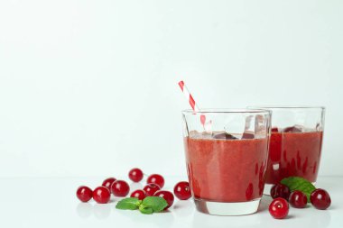 Bir bardak vişneli buzlu içecek ve malzemeler beyaz masada.