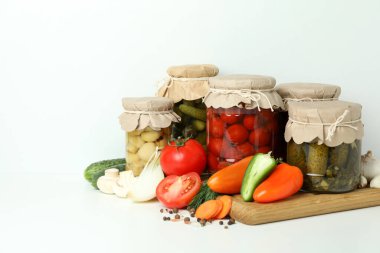Kavanozlar dolusu sebze turşusu ve malzemeler beyaz masada.