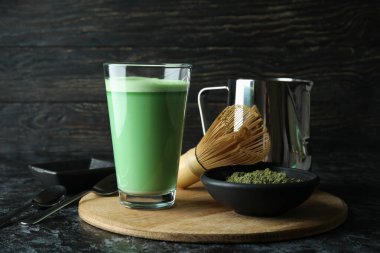 Siyah dumanlı masayı hazırlamak için bir bardak matcha latte ve aksesuarlar.