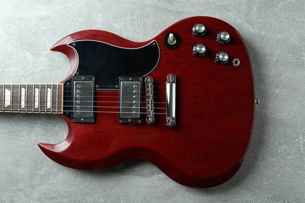 Red electric guitar on gray textured background