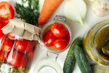 Kavanozlar dolusu sebze turşusu ve malzemeler beyaz masada.