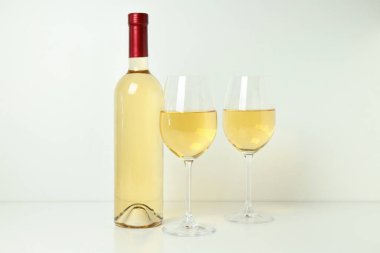 Şişe ve bardaklar beyaz masada.