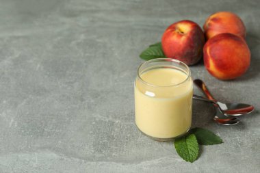 Kavanozlu şeftalili yoğurt, şeftalili ve kaşıklı gri arka plan