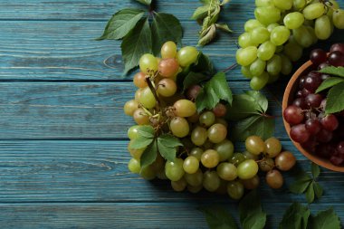 Kırmızı üzümlü kase ve ahşap zemin üzerinde yeşil üzüm.