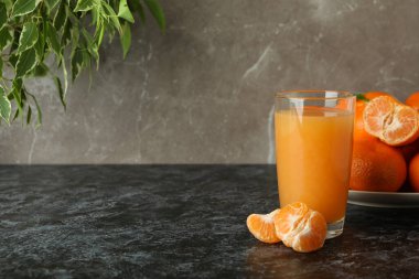 Mandalina suyu ve malzemeler siyah dumanlı masada.